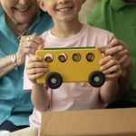 Child holding yellow wooden school bus that was made by the Emerald Heights wood working crew